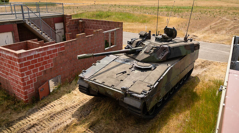Een CV90 schuilt tussen twee gebouwen