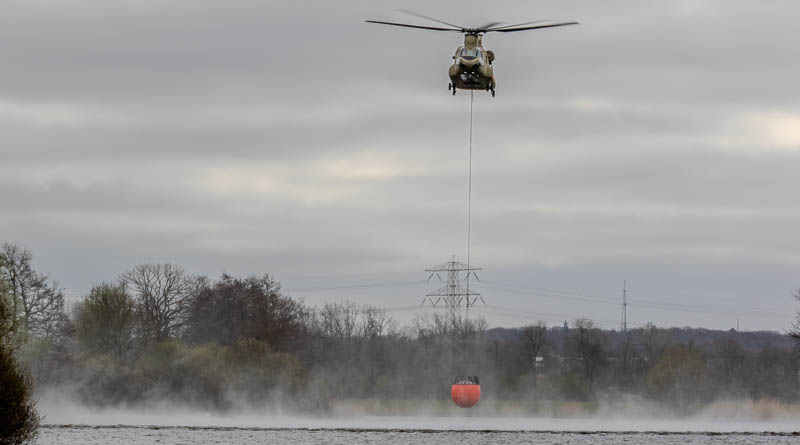 Helikopter die boven rivier vliegt met waterzak