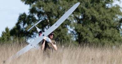 Een man loopt met een drone door het hoge gras