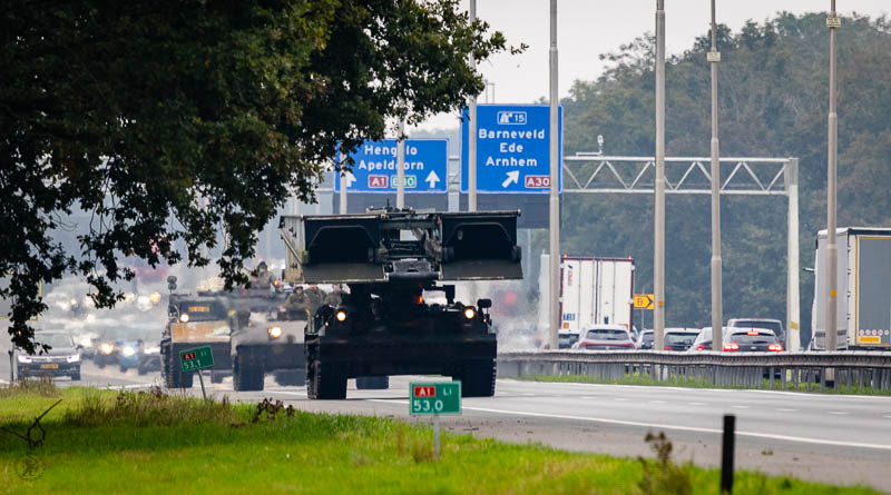 Rupsvoertuigen op een snelweg met op de achtergrond verkeersborden