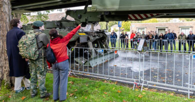 Een bezoeker in rode jas wijst naar de brug van een Leguaan bruglegtank