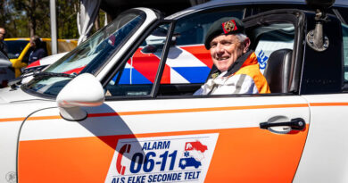 Militair met baret op in oude politieauto