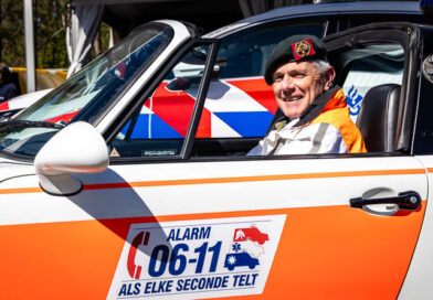 Militair met baret op in oude politieauto