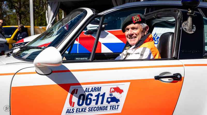 Militair met baret op in oude politieauto