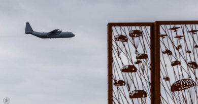 Een Hercules transportvliegtuig op de achtergrond met het Edese monument op de voorgrond