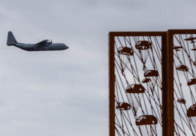 Een Hercules transportvliegtuig op de achtergrond met het Edese monument op de voorgrond