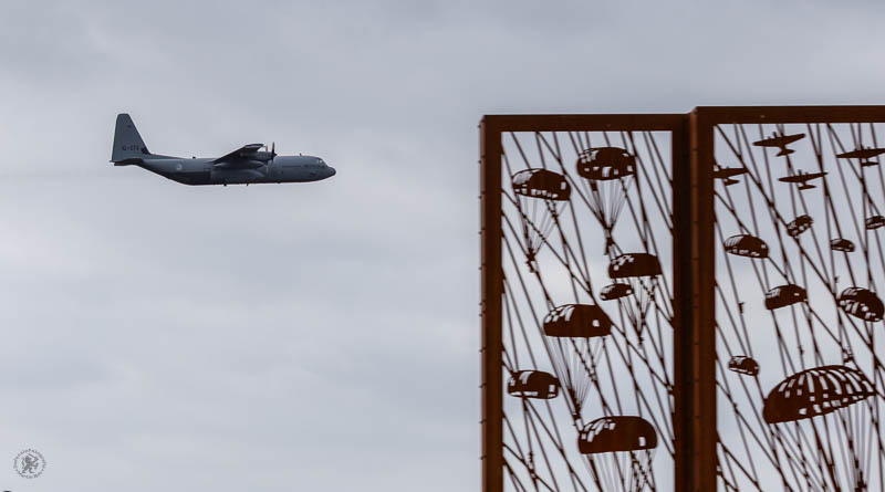 Een Hercules transportvliegtuig op de achtergrond met het Edese monument op de voorgrond
