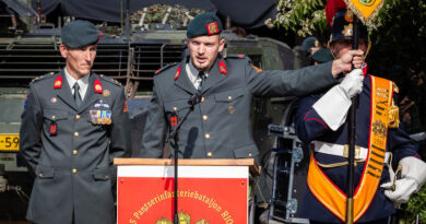 Een militair houdt het vaandel vast en zegt de eed op. Zijn commandant kijkt toe.