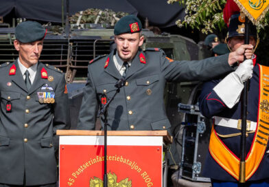 Een militair houdt het vaandel vast en zegt de eed op. Zijn commandant kijkt toe.