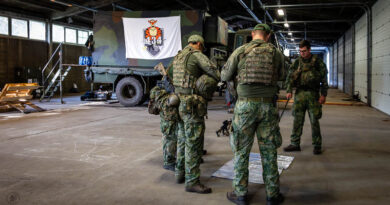 Militairen rond een kaart met op de achtergrond het logo van 434 Herstel