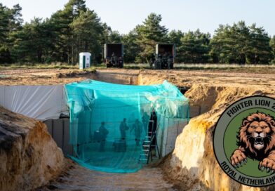 Zandvlakte met een bouwsel onder drone-netten