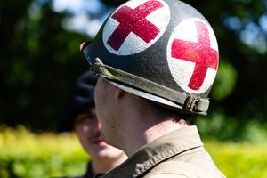 Amerikaanse legerhelm met witte cirkels en daarop een rood kruis.